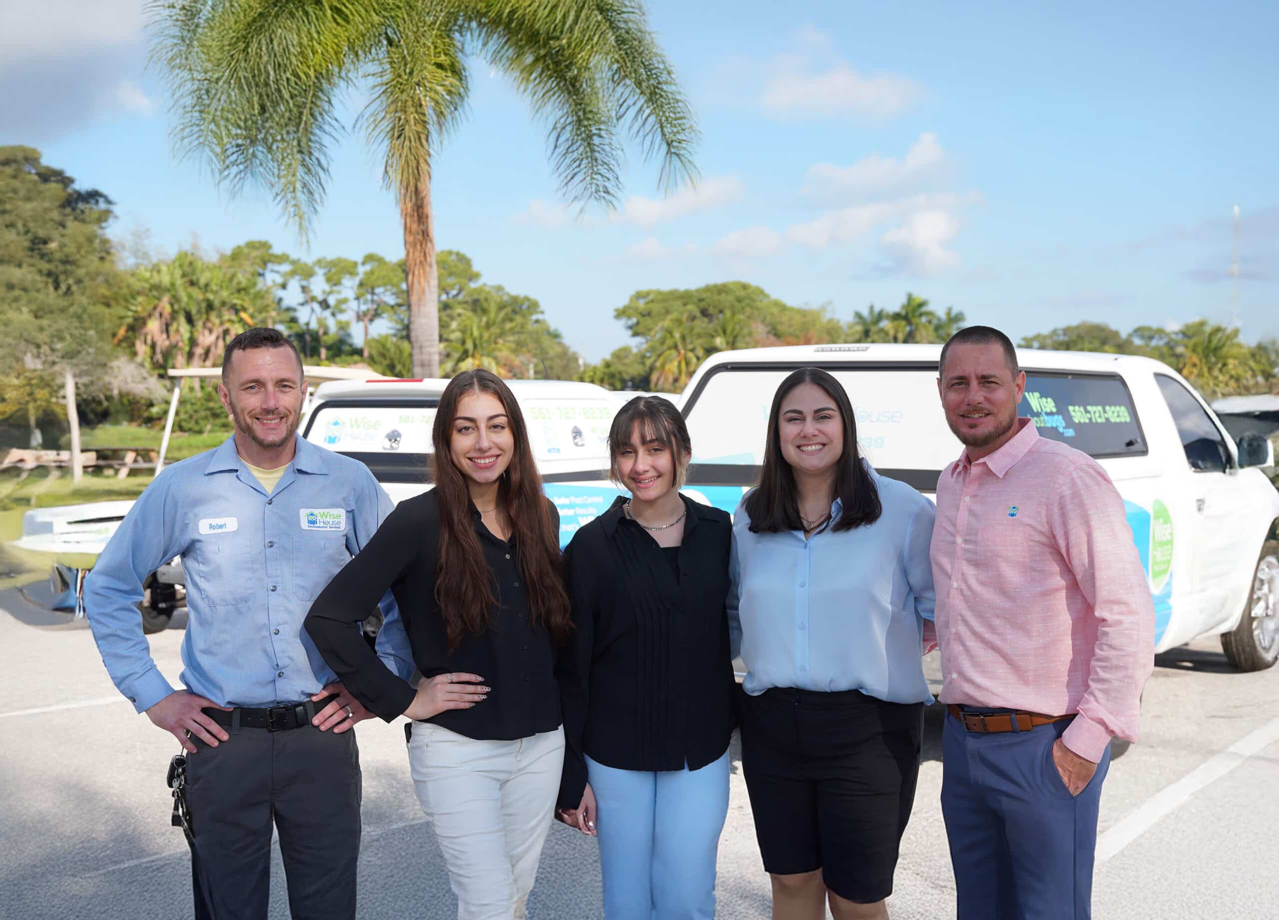 Wise House Environmental Services team standing together outdoors in front of branded service vehicles in Palm Beach County, Florida
