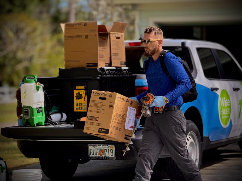 Wise House Bugs pest control technician unloading bait station equipment from a service truck