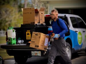 Wise House Bugs pest control technician unloading bait station equipment from a service truck