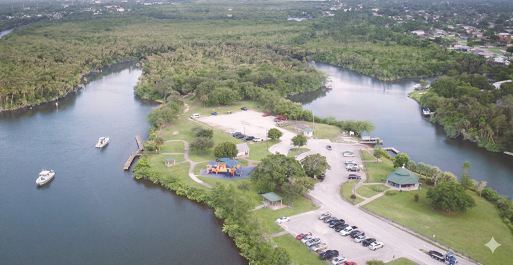 High-definition aerial drone photography of a local Florida town park with a marina, playground, and lush tree coverage, demonstrating a professional pest control service area.